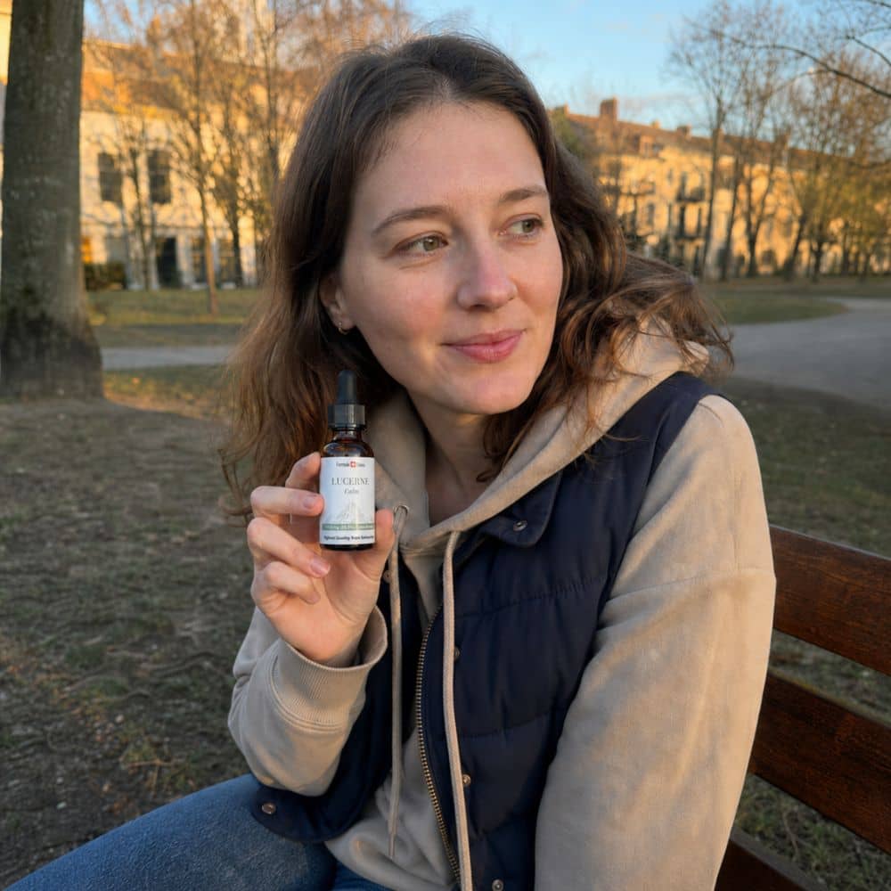 Femme tenant un flacon d'huile de CBD Lucerne en plein air, dans un parc