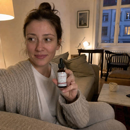 Femme tenant un flacon d'huile de CBD St. Moritz dans un salon