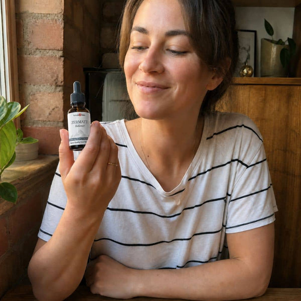 Femme tenant une bouteille d'huile de CBD Zermatt dans un cadre intérieur confortable.